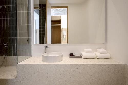 a bathroom with a sink and a mirror at Odina Hotel in Watthana Nakhon
