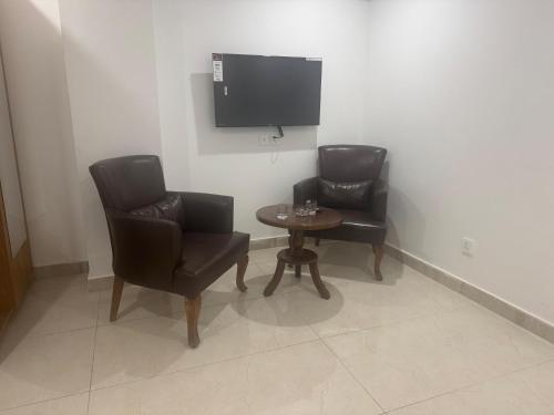 una camera con due sedie, un tavolo e una TV di Best Inn Hotel a Murree