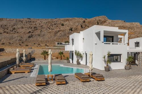 eine Villa mit einem Swimmingpool mit Stühlen und Sonnenschirmen in der Unterkunft Amani Villa Lindos Two in Lindos