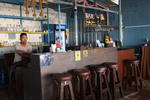 a man sitting at a counter in a bar with stools at Nirvana Beach Cottages in Canacona