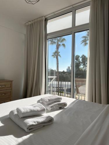 a bedroom with a bed with towels on it and a window at Almyria Apartments - By NOMA STAYS Cyprus in Paphos