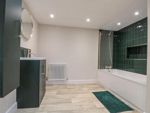 baño con lavabo y ducha con azulejos verdes en Dotty's Den, en Bridlington