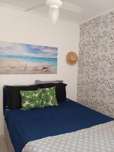 a bedroom with a bed with blue sheets and green pillows at Beira mar 2 in Santos