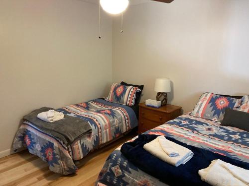 ein Zimmer mit zwei Betten und einem Tisch mit einer Lampe in der Unterkunft Pico Killington Ski Cabin Mtn View Wood Stove in Mendon