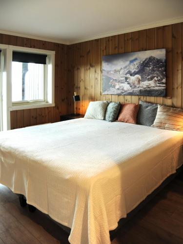 a large white bed in a bedroom with wooden walls at Apartment in Gol Skisenter in Gol