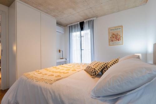 ein weißes Schlafzimmer mit einem Bett mit Kissen und einem Fenster in der Unterkunft Live Smart in Montevideo