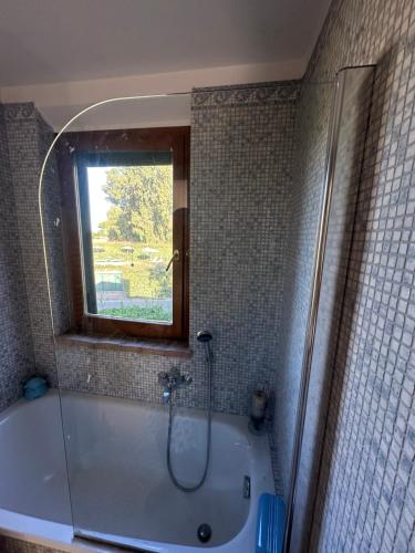 a bathroom with a bath tub with a window at Villa a Capalbio in Carige Bassa
