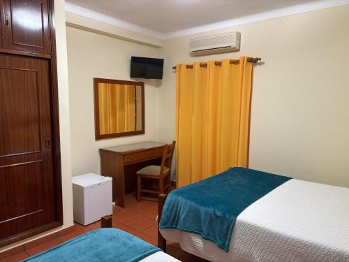 a bedroom with a bed and a desk and a mirror at Residencial Idalio in Odemira
