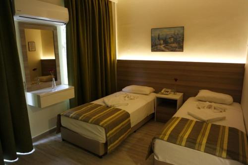 a hotel room with two beds and a mirror at Amphi Apart in Marmaris