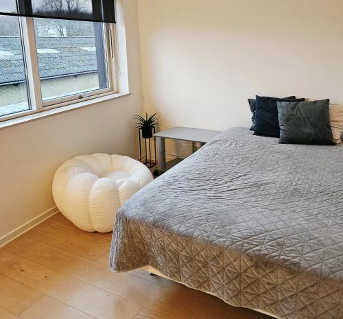 a bedroom with a bed and a chair next to a window at Easy stay in Glostrup