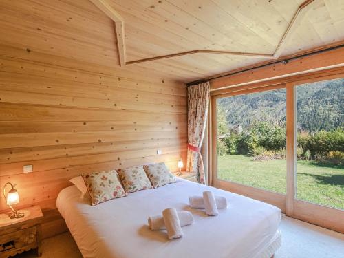 Bett in einem Holzzimmer mit einem großen Fenster in der Unterkunft Chalet authentique près de Chamonix avec jardin et parking - FR-1-343-182 in Chamonix-Mont-Blanc