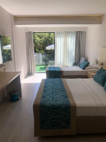 a bedroom with two beds and a large window at Pirates Park Resort - All Inclusive in Kemer