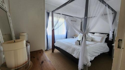 ein Schlafzimmer mit einem Himmelbett mit weißen Vorhängen in der Unterkunft Bella Casa1 in Velddrif