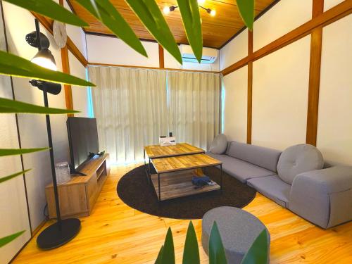 a living room with a couch and a tv at MM HOUSE Near Takamatsu Station 徒歩3分無料駐車場1台有り in Takamatsu