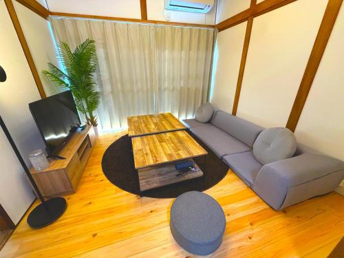 a living room with a couch and a tv at MM HOUSE Near Takamatsu Station 徒歩3分無料駐車場1台有り in Takamatsu
