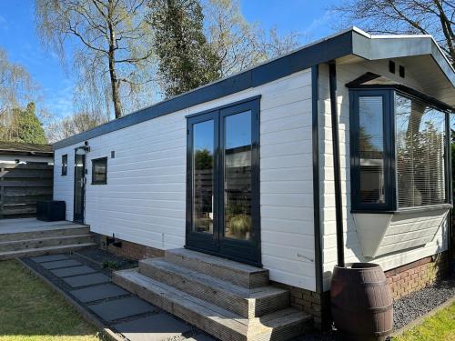 a white tiny house with stairs and windows at NatuurChalet - Rust op de Veluwe, Prive tuin en BBQ in Putten