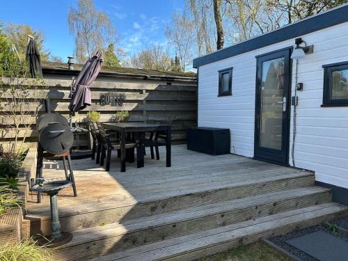 a wooden deck with a table and an umbrella at NatuurChalet - Rust op de Veluwe, Prive tuin en BBQ in Putten