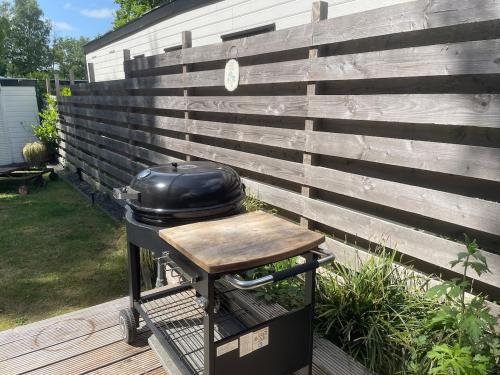 a grill sitting on a cart next to a fence at NatuurChalet - Rust op de Veluwe, Prive tuin en BBQ in Putten