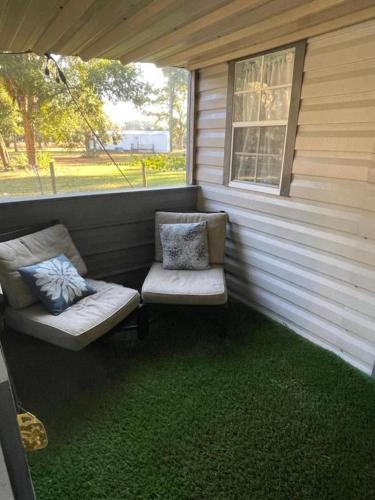 a screened in porch with two chairs and a window at Neals Nest Cozy Cabin in Chiefland