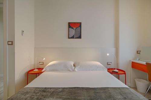 a bedroom with a large white bed with two red tables at THE ROOMS - Serviced Apartments Tirana in Tirana