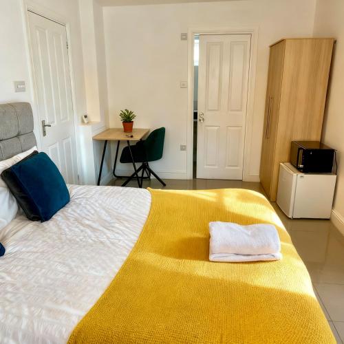 a bedroom with a large bed with a yellow blanket at Flexistay Studio at Watford in Watford