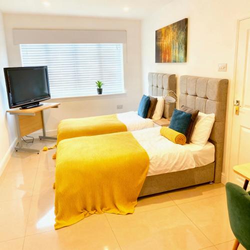 a bedroom with a large bed with a yellow blanket at Flexistay Studio at Watford in Watford