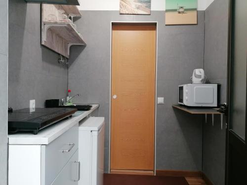 eine Küche mit Holztür und Mikrowelle in der Unterkunft A casinha in Nazaré