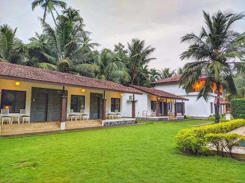 une maison avec une pelouse verte devant dans l'établissement Ice Apple Resort By Vintara Stays, à Nagaon