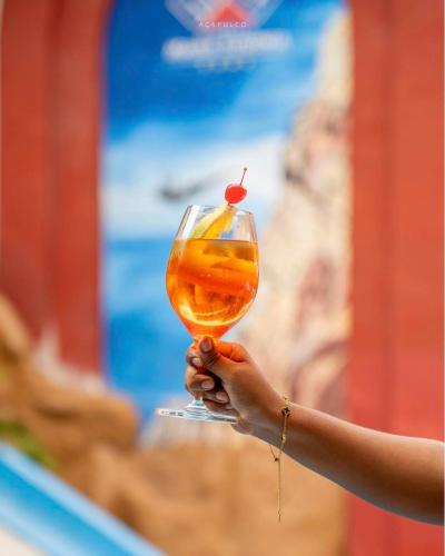 a person holding a wine glass with a cherry on it at Hotel Hacienda María Eugenia Acapulco in Acapulco