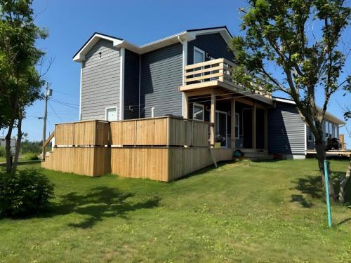 a house with a wooden fence in a yard at Oceanfront Cottage w/ Upper Balcony View in Summerside