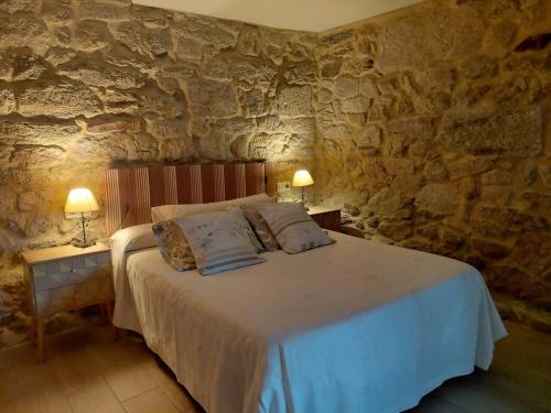 a bedroom with a bed in a stone wall at Piedra Miranda in Vilaboa