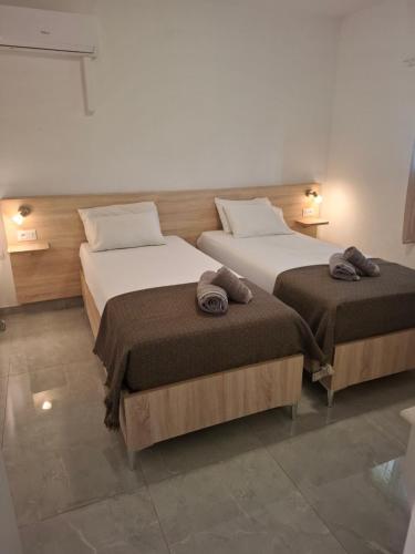 two beds in a hotel room with towels on them at Βessie's Village in Kefallonia