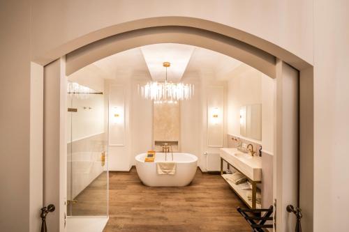 La salle de bains est pourvue d'une baignoire blanche et d'un lustre. dans l'établissement Hotel Kasteel Oost, à Fauquemont