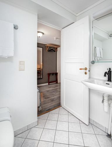 a white bathroom with a sink and a mirror at Kjøbmandsgaarden Hotel in Mandal