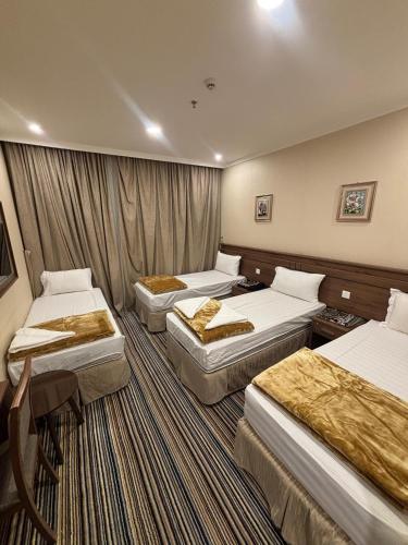 ein Hotelzimmer mit 3 Betten und einem Tisch in der Unterkunft فندق قصر ماريوت 1 in Al ‘Azīzīyah