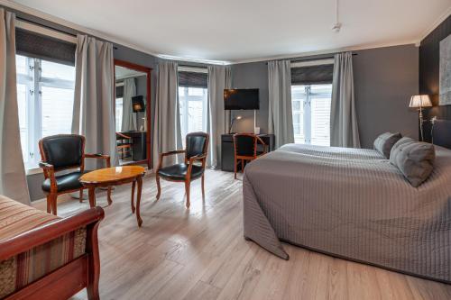 a bedroom with a bed and a table and chairs at Kjøbmandsgaarden Hotel in Mandal
