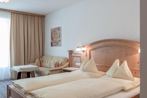 a hotel room with two beds and a chair at Alpenresidenz am Mühlbach in Obergurgl