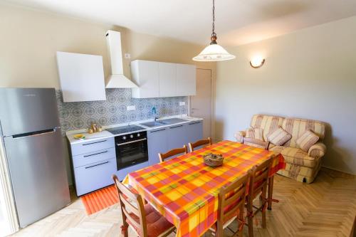 a kitchen with a table with chairs and a refrigerator at Corte Girodo - Appartamento Girasole in Rubiana