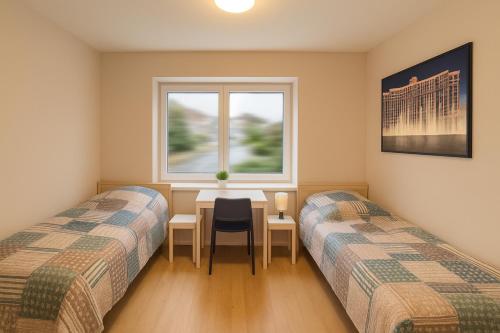 two beds in a room with a table and a window at Ferienwohnung Las Vegas in Marienheide