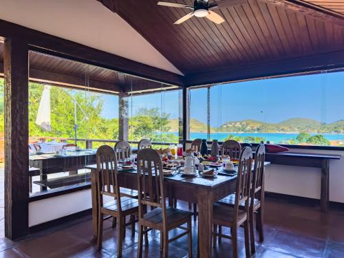 a dining room with a table and chairs and windows at Pousada Encanto de Búzios in Búzios