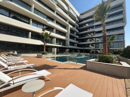 a large apartment building with lounge chairs and a swimming pool at Amazing Dubai Silicon Oasis Rental Apartments in Dubai