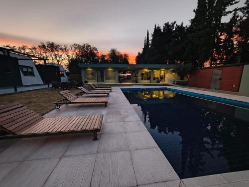 einen Pool mit Bänken neben einem Gebäude in der Unterkunft CasAmigos Cruz de Piedra in Maipú