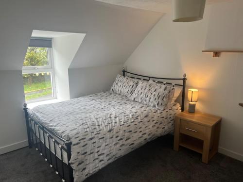 a bedroom with a bed and a window and a night stand at Highland Park Cottage in Kirkwall