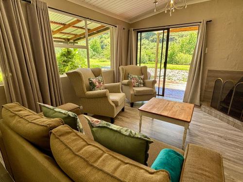 ein Wohnzimmer mit Sofa, Stühlen und einem Tisch in der Unterkunft Meadow Lane Country Cottages in Underberg
