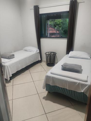 zwei Betten in einem Zimmer mit Fenster in der Unterkunft Conexão conforto in Vespasiano