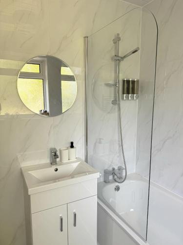 a white bathroom with a sink and a shower at Stansted Stop Over in Takeley