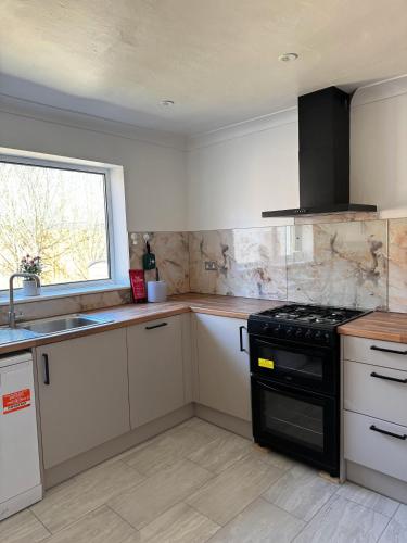 a kitchen with white cabinets and a black stove at Stansted Stop Over in Takeley
