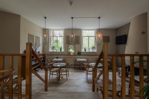 a dining room with tables and chairs and windows at Hotel Randduin in Oostkapelle