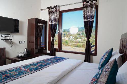 une chambre avec un lit et une grande fenêtre dans l'établissement Sukoon Inn Hotel & Restaurant, à Someshwar