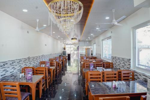 une salle à manger avec tables et chaises et un lustre dans l'établissement Sukoon Inn Hotel & Restaurant, à Someshwar